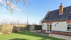 A house with a sloped roof, a brick chimney, and a small front porch. - Saddle Rack Cottage (Louth)