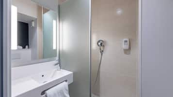 Un baño moderno con cabina de ducha de vidrio, un lavabo blanco y un espejo.