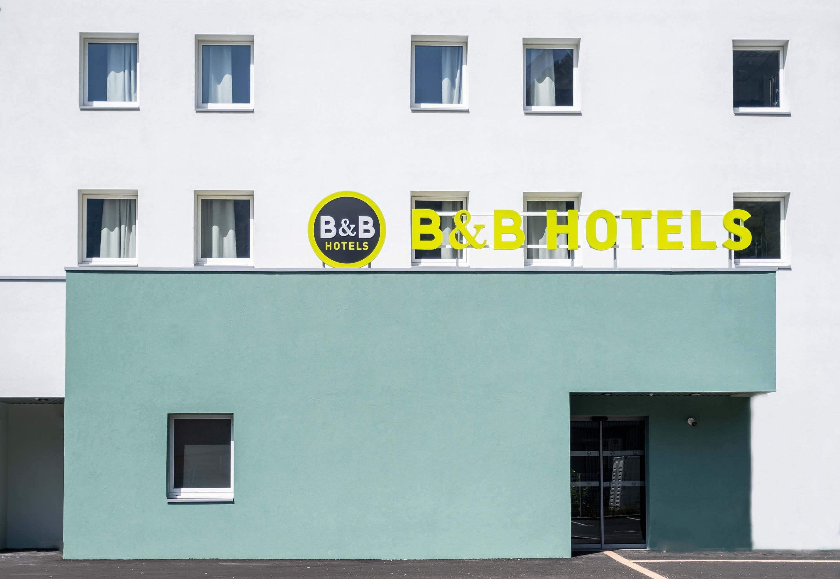 A building with a B&B Hotels sign, featuring a modern design with a flat roof and a light blue facade.