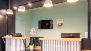 Zona de recepción con dos mostradores, un televisor de pantalla plana y una orquídea en maceta.