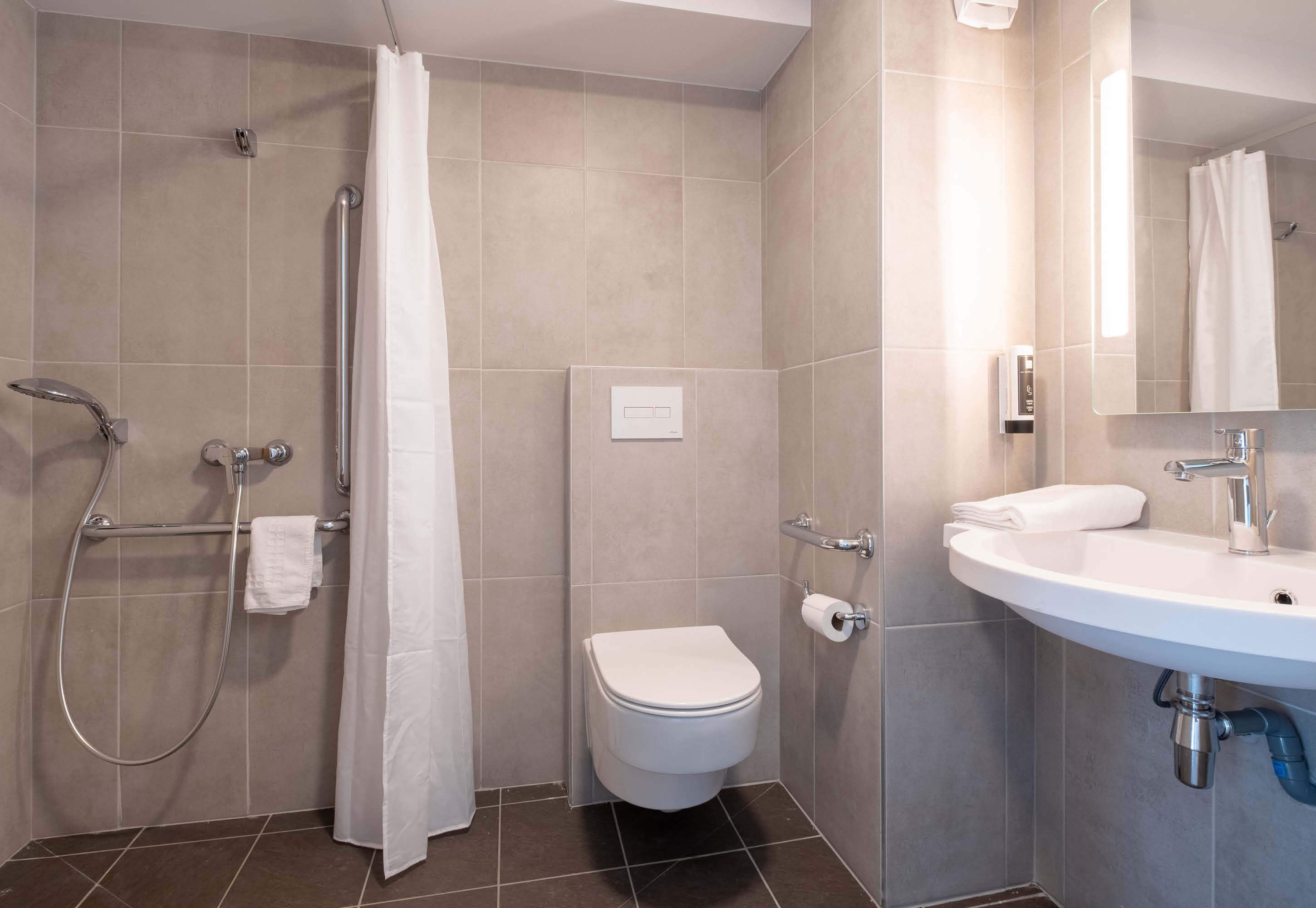 A modern bathroom with a shower, toilet, and sink.