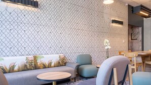 Un área de estar moderna con pared decorada, disposición de asientos y una mesa.