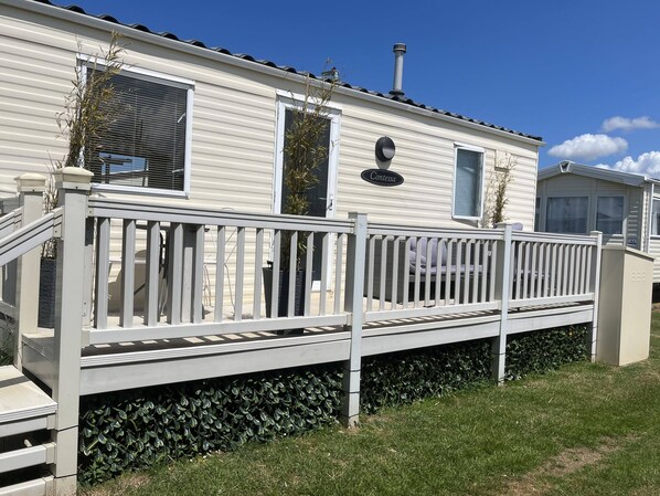 A mobile home with a white exterior, a balcony with a white railing, and a chimney.