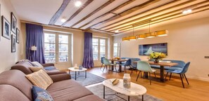 Un salon moderne comprenant un ensemble de canapés, un coin repas et de grandes fenêtres avec des rideaux.