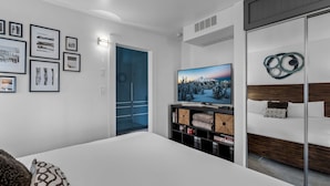 Ein modernes Schlafzimmer mit einem großen Bett, einem Fernseher und einem Kleiderschrank.