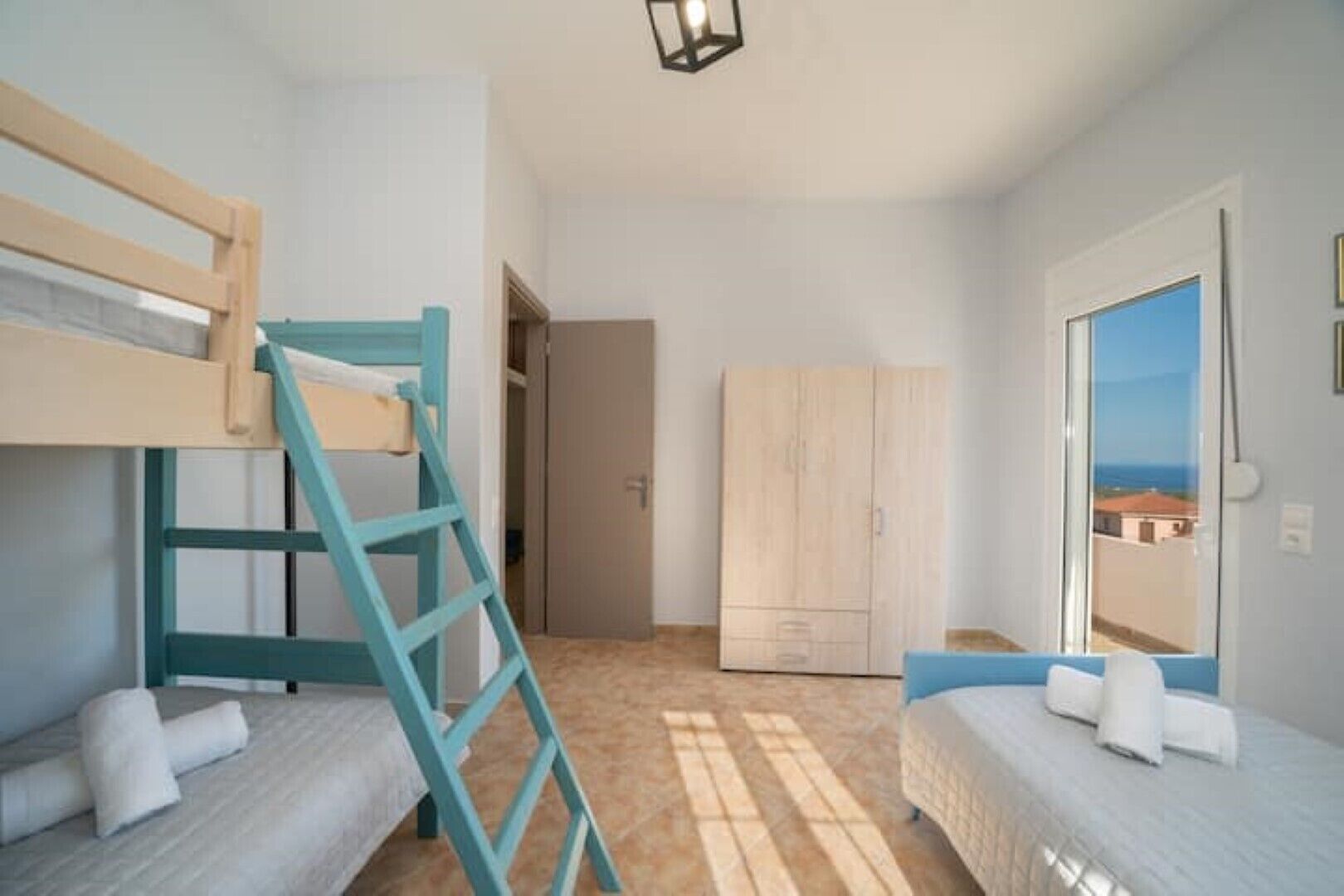 Un dormitorio con literas, un armario y vistas por la ventana.