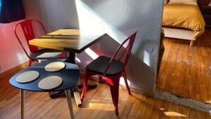A room with a bed, a table with chairs, and a window.