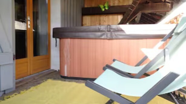 A hot tub with a wooden deck and a yellow mat in front.