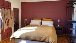 A bedroom with a bed, two bedside tables, a wardrobe, and a chandelier.
