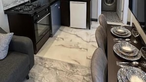 Uma cozinha moderna com área de jantar, sofá e televisão.