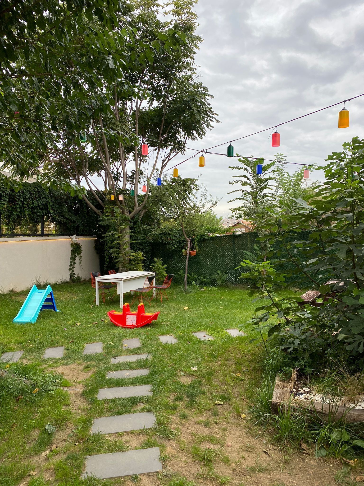 A backyard with a play area including a slide and a small table with chairs.