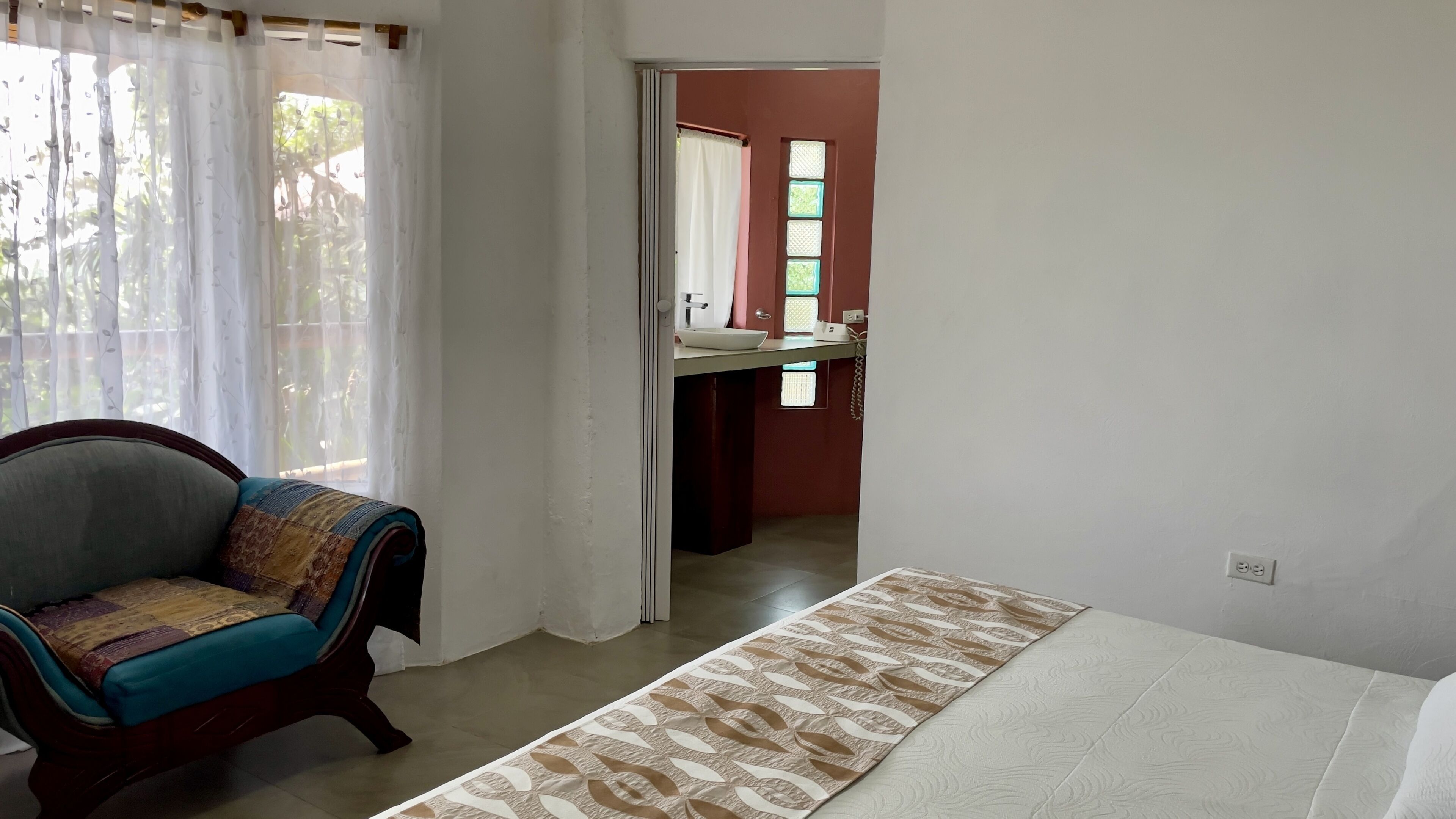 Un dormitorio con cama, una silla y vistas al baño.