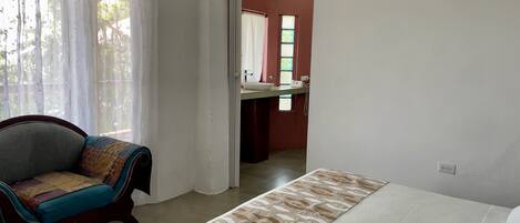 Un dormitorio con cama, una silla y vistas al baño.
