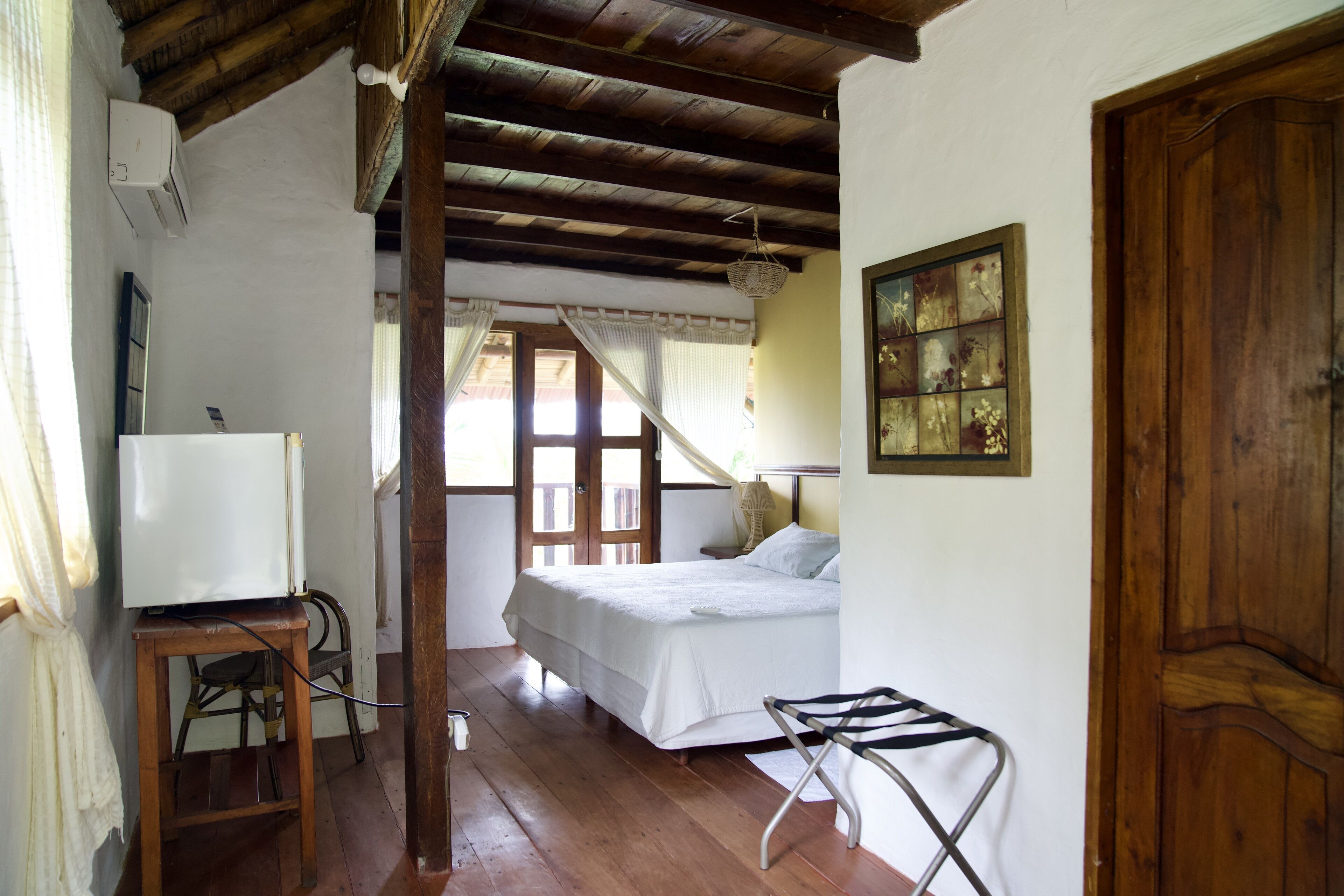 A bedroom with a wooden ceiling, a bed, a TV on a small table, and a door.