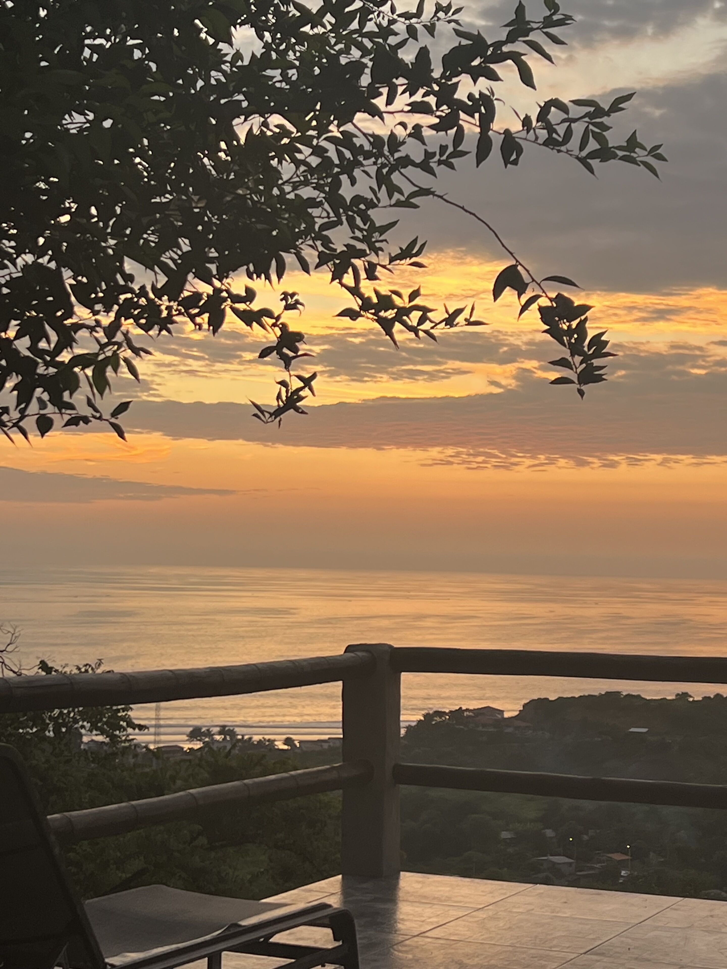 Un banco con vista a un atardecer, con barandilla en primer plano.