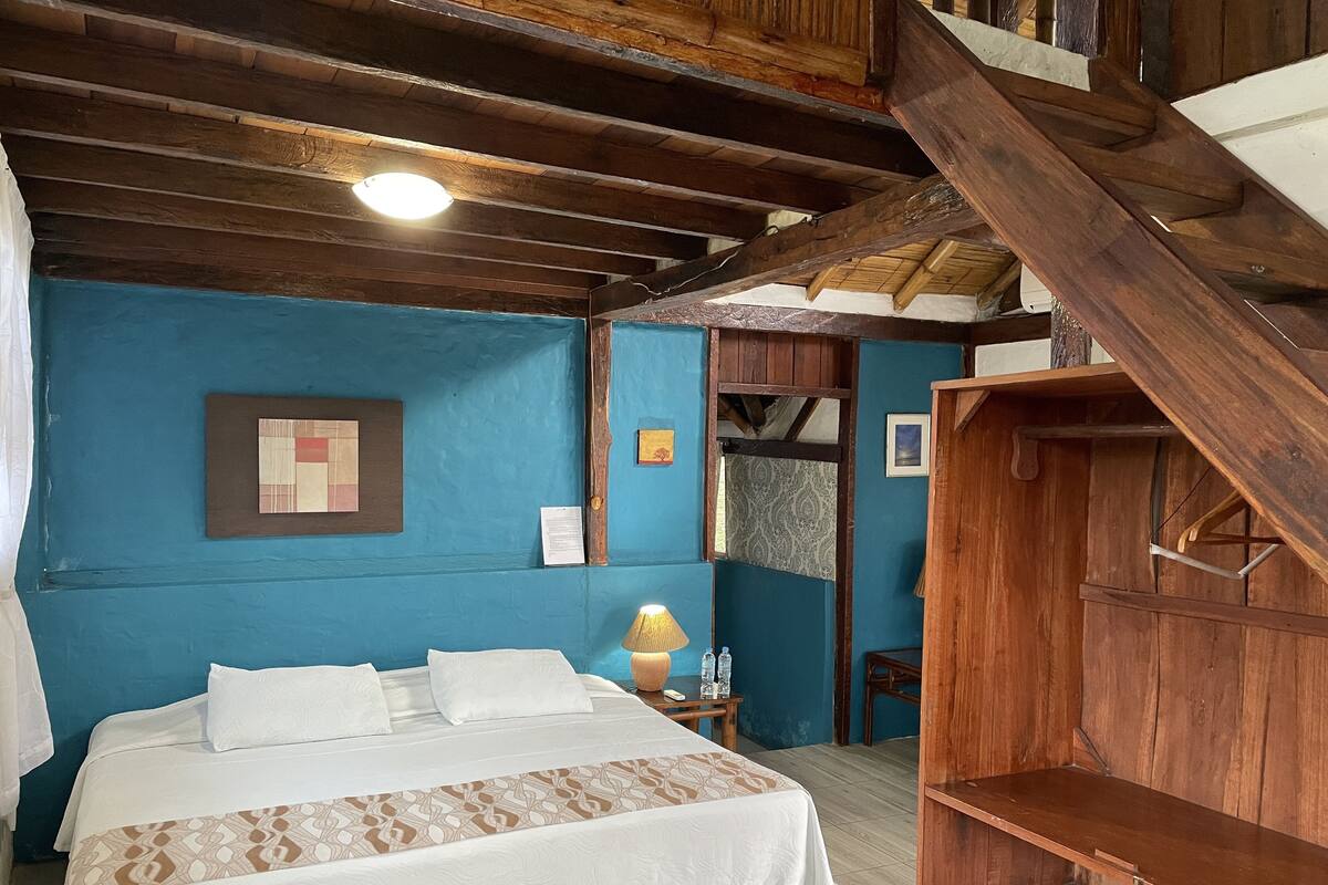 A bedroom with a bed, a wooden wardrobe, and a blue wall.