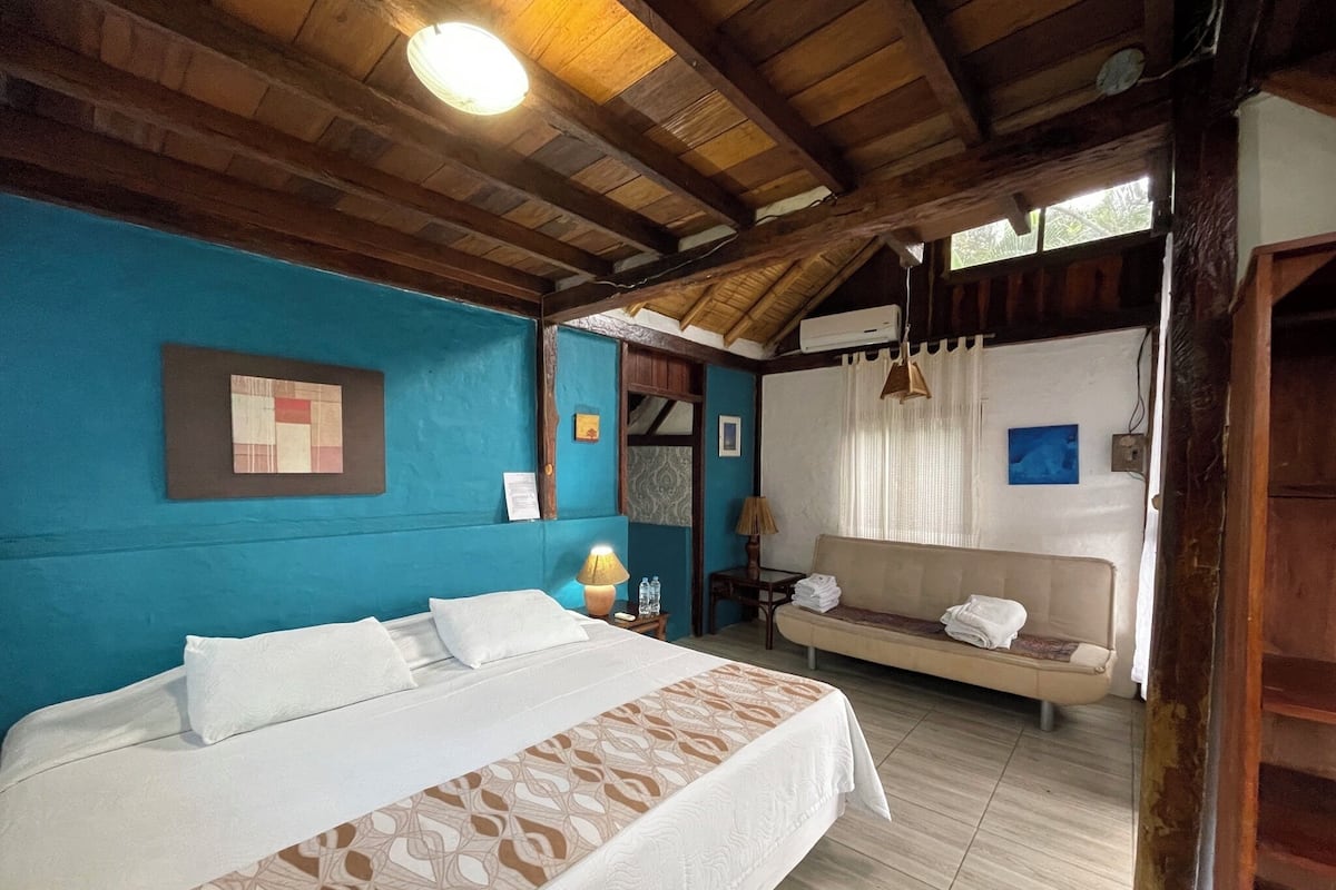 Quarto com cama, sofá e janela com cortinas.