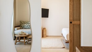Um quarto com cama, mesa de madeira, tapete tecido e televisão na parede.