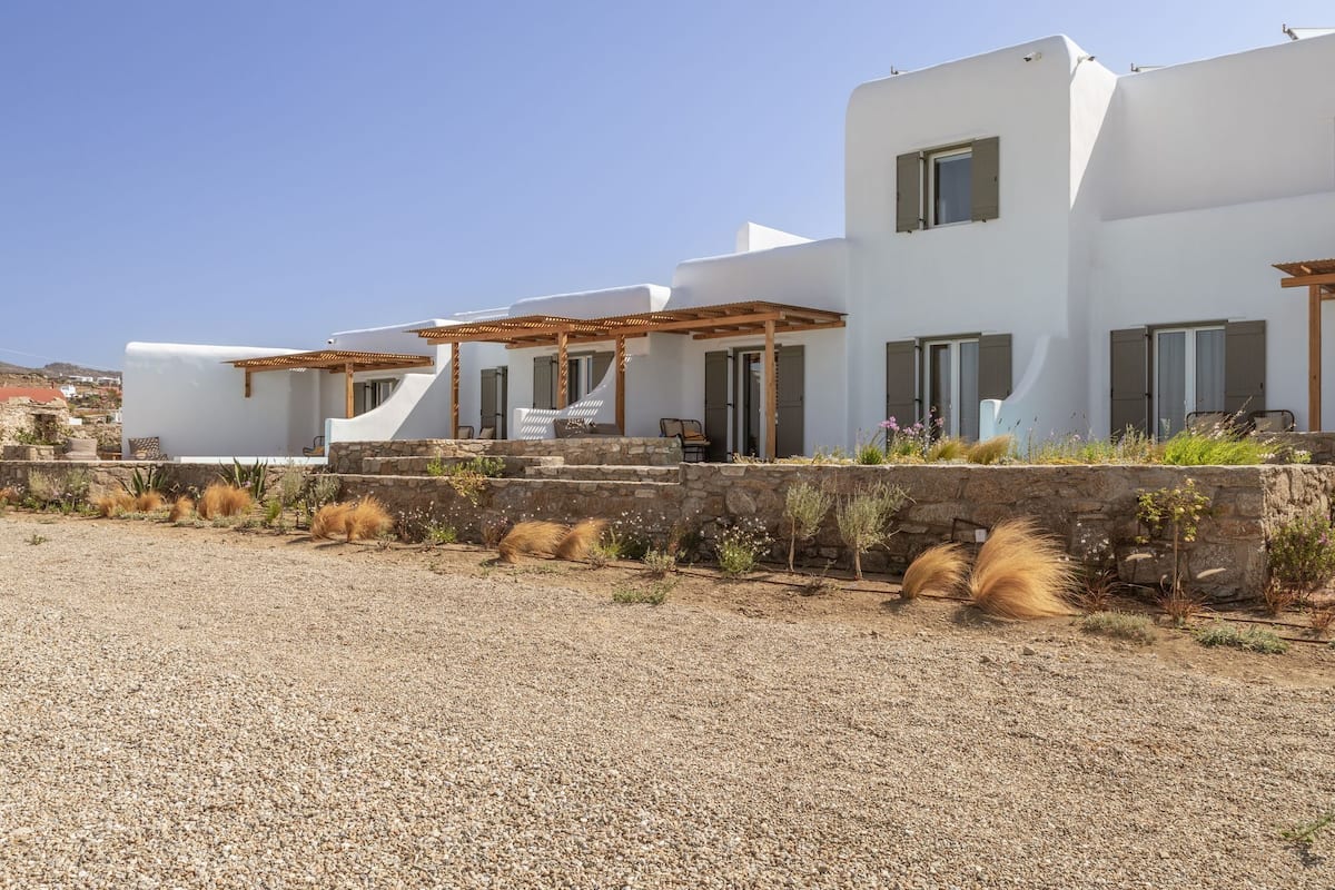 A modern white building with a stone retaining wall and a gravel driveway.