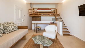 Um espaço compacto para viver, com beliche, sofá, poltrona e pequena área de trabalho.
