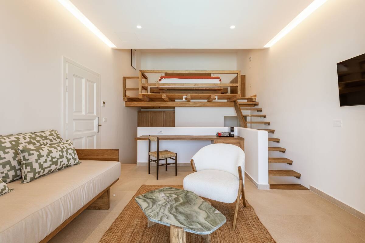 A compact living space with a bunk bed, a sofa, a chair, and a small desk area.