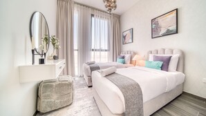 Una habitación de hotel moderna con una cama grande, una mesita de noche, un espejo y una ventana con cortinas.
