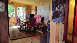 Ein Holzinnenraum mit Esstisch und Stühlen, einem Spiegel und einem gerahmten Bild an der Wand.