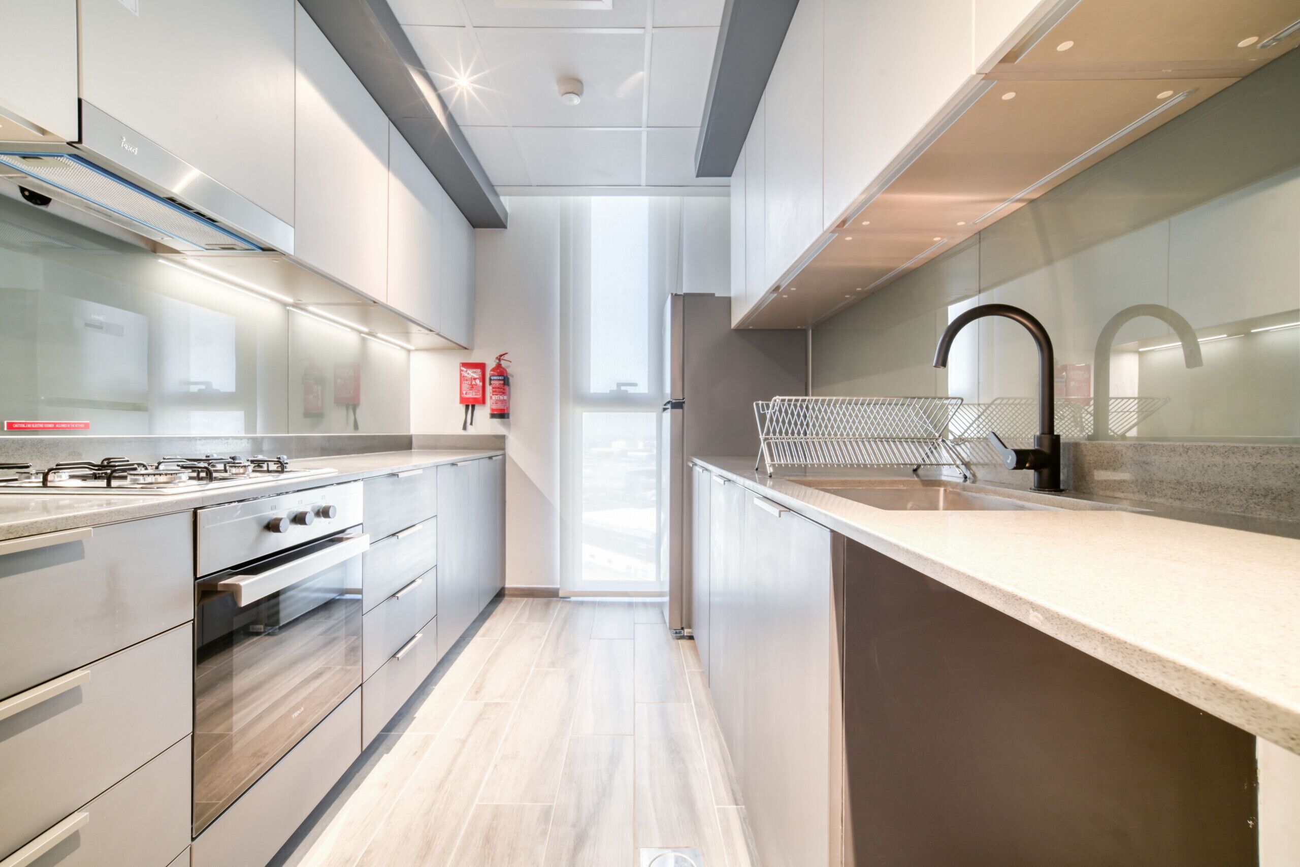 Ett modernt kök med rostfria vitvaror, en väggbeklädnad av glas och en stilren design.