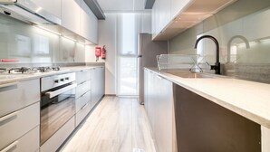 A modern kitchen with stainless steel appliances, a glass backsplash, and a sleek design. - Exquisite 2BR w/ Assistant’s Room at Mesk 1 Midtown Dubai Production City by Deluxe Holiday Homes (Dubai)