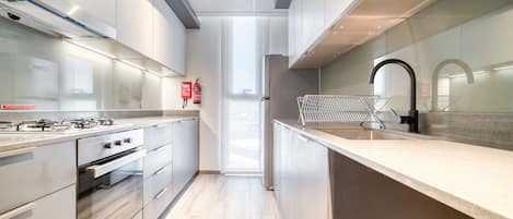 Ett modernt kök med rostfria vitvaror, en väggbeklädnad av glas och en stilren design.