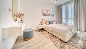 A modern bedroom with a large bed, bedside tables, a mirror, and a chandelier. - Exquisite 2BR w/ Assistant’s Room at Mesk 1 Midtown Dubai Production City by Deluxe Holiday Homes (Dubai)
