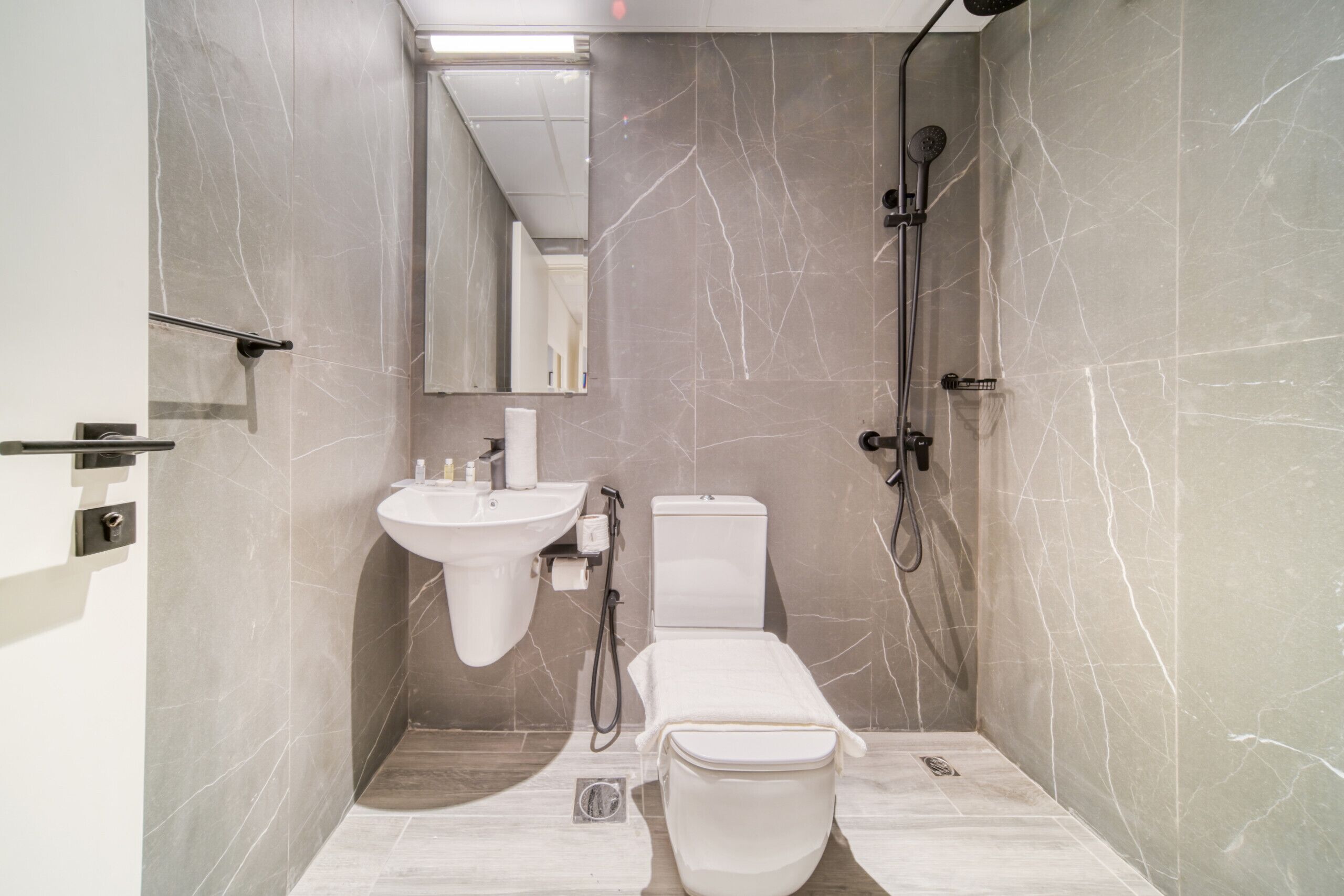 Ein modernes Badezimmer mit Waschbecken, Toilette und Dusche, alles in Weiß.