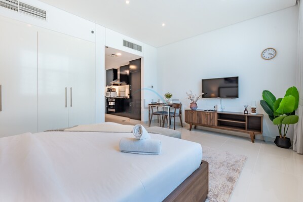 Una camera d'albergo moderna con un letto grande, una TV, un angolo ristoro e una pianta.