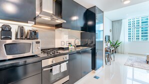A modern kitchen with stainless steel appliances, a built-in oven, and a sleek black cabinetry. - Canal View, Walking Distance to Bay Avenue Mall, Mins to Downtown Dubai (Dubai)