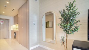 A modern interior with a wooden cabinet, a potted plant, and a framed picture on a console table. - Heavenly Studio at The Palm Tower Palm Jumeirah by Deluxe Holiday Homes (Dubai)
