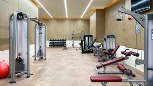 A modern gym with various exercise equipment, including weight machines, benches, and dumbbells. - Heavenly Studio at The Palm Tower Palm Jumeirah by Deluxe Holiday Homes (Dubai)