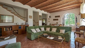 Un soggiorno ampio con un divano a divano verde, una libreria in legno, un tavolino da caffè in vetro e una scala con soffitto in mattoni.