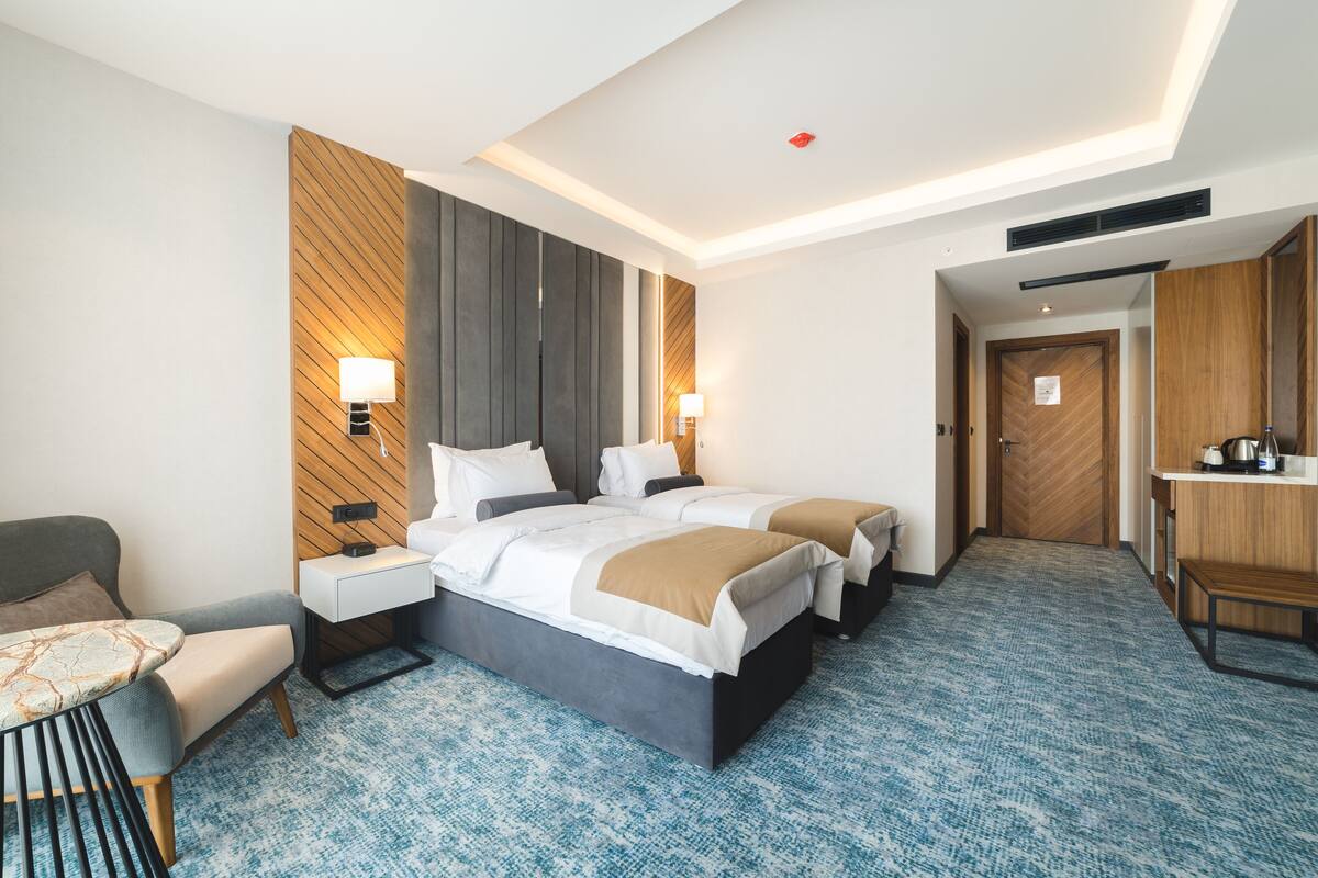Una habitación de hotel con una cama grande, mesitas de noche, un escritorio y una silla.