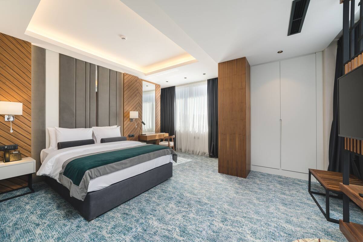 Una habitación de hotel moderna con una cama grande, un escritorio, una silla y un televisor.
