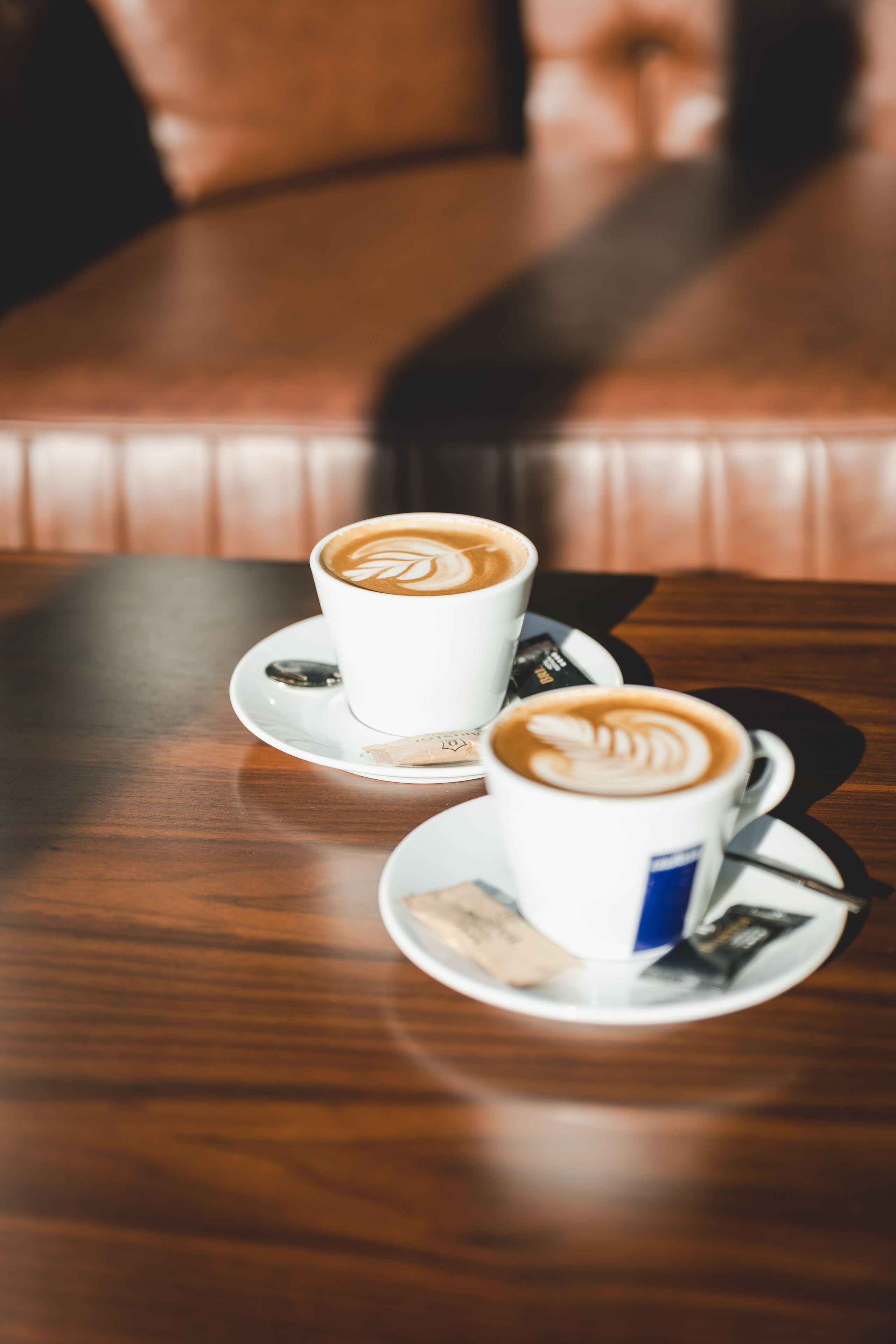 Dos tazas de café sobre platillos en una mesa de madera.