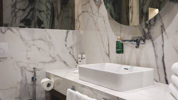 A bathroom with a white marble sink, a mirror, a towel rack, and a toilet paper holder.