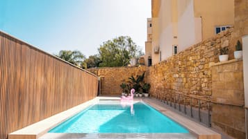 Una piscina al aire libre, sillones reclinables de piscina
