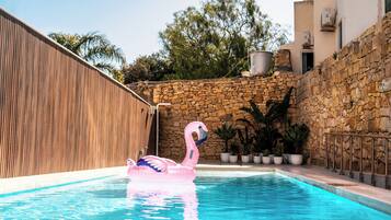 Una piscina al aire libre, sillones reclinables de piscina