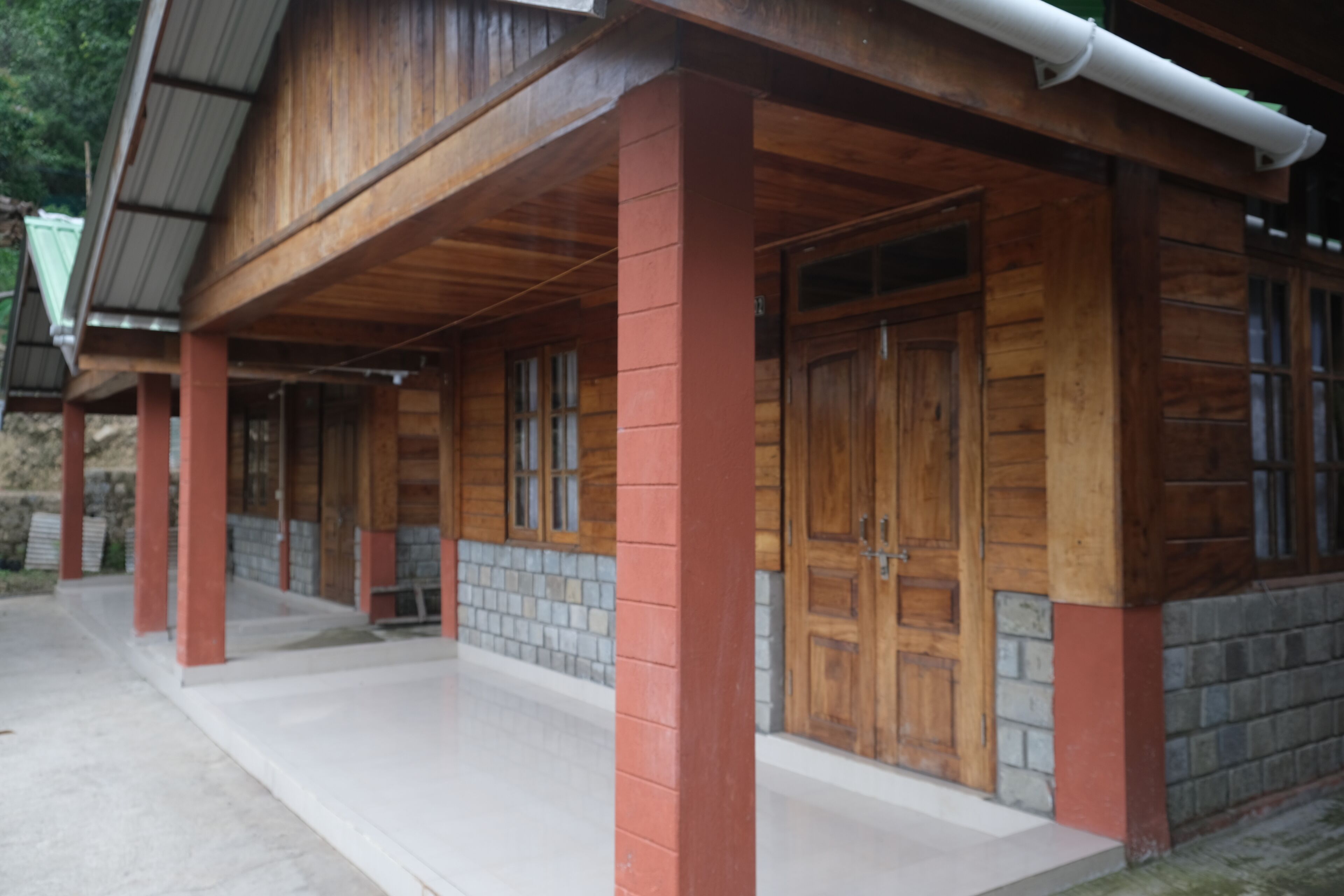 A wooden building with a porch, large wooden doors, and a tiled floor.