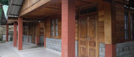 A wooden building with a porch, large wooden doors, and a tiled floor.