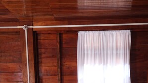 A neatly made bed with white linens and pillows, a wooden headboard, and a nightstand with a lamp. - Camp David (Kohima)
