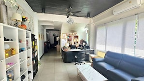 Un salon spacieux avec un plafond sombre, un canapé bleu, une table basse blanche et une bibliothèque remplie de divers objets.
