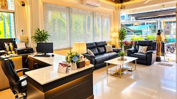 A modern hotel lobby with a reception desk, seating area, and large windows.