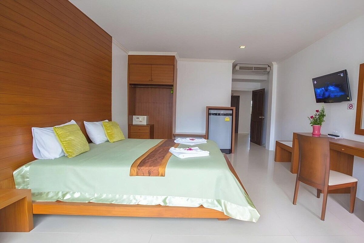 Una habitación de hotel con cama, escritorio, televisor y espejo.