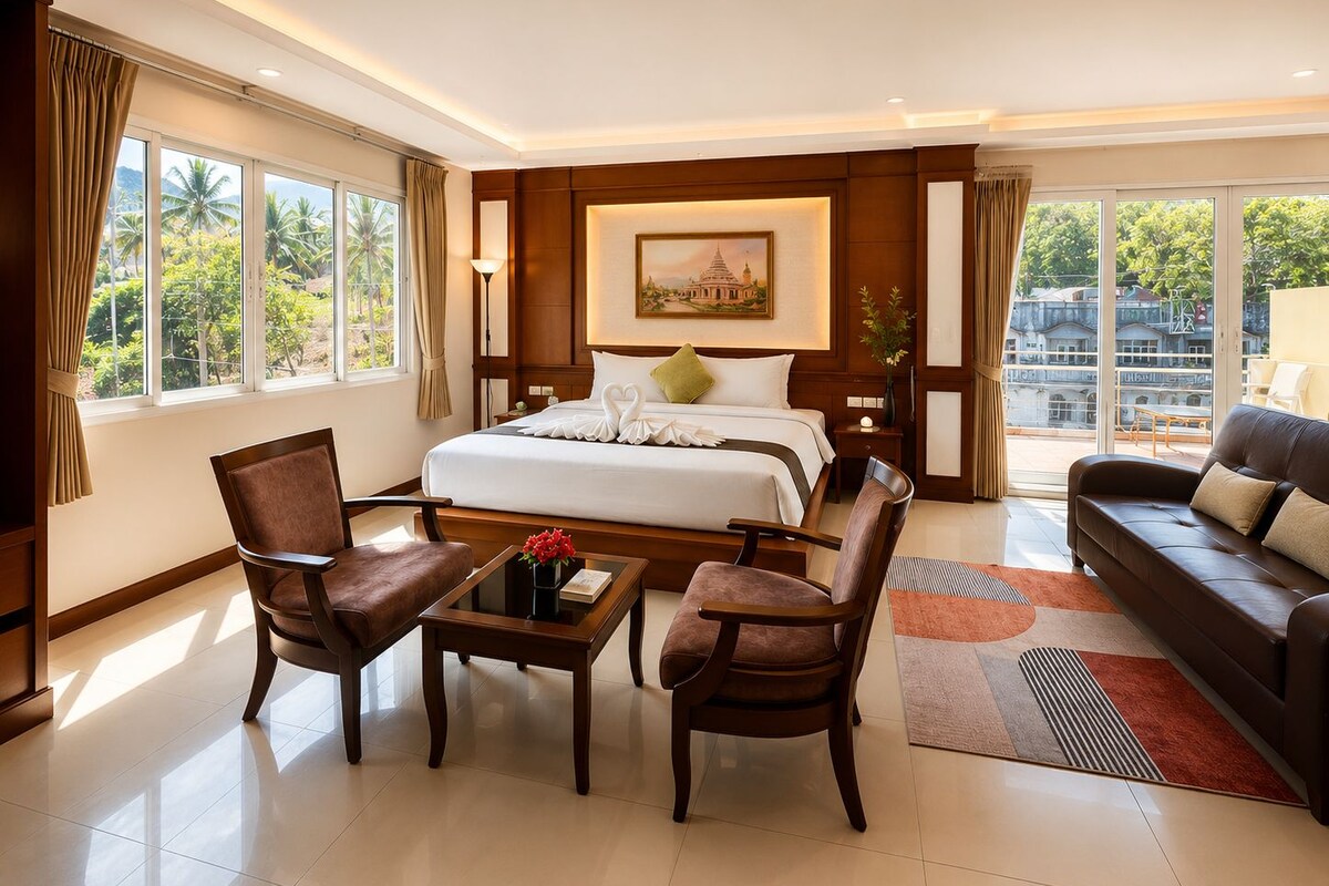 A hotel room with a large bed, two armchairs, a sofa, a small table with flowers, and a painting on the wall.